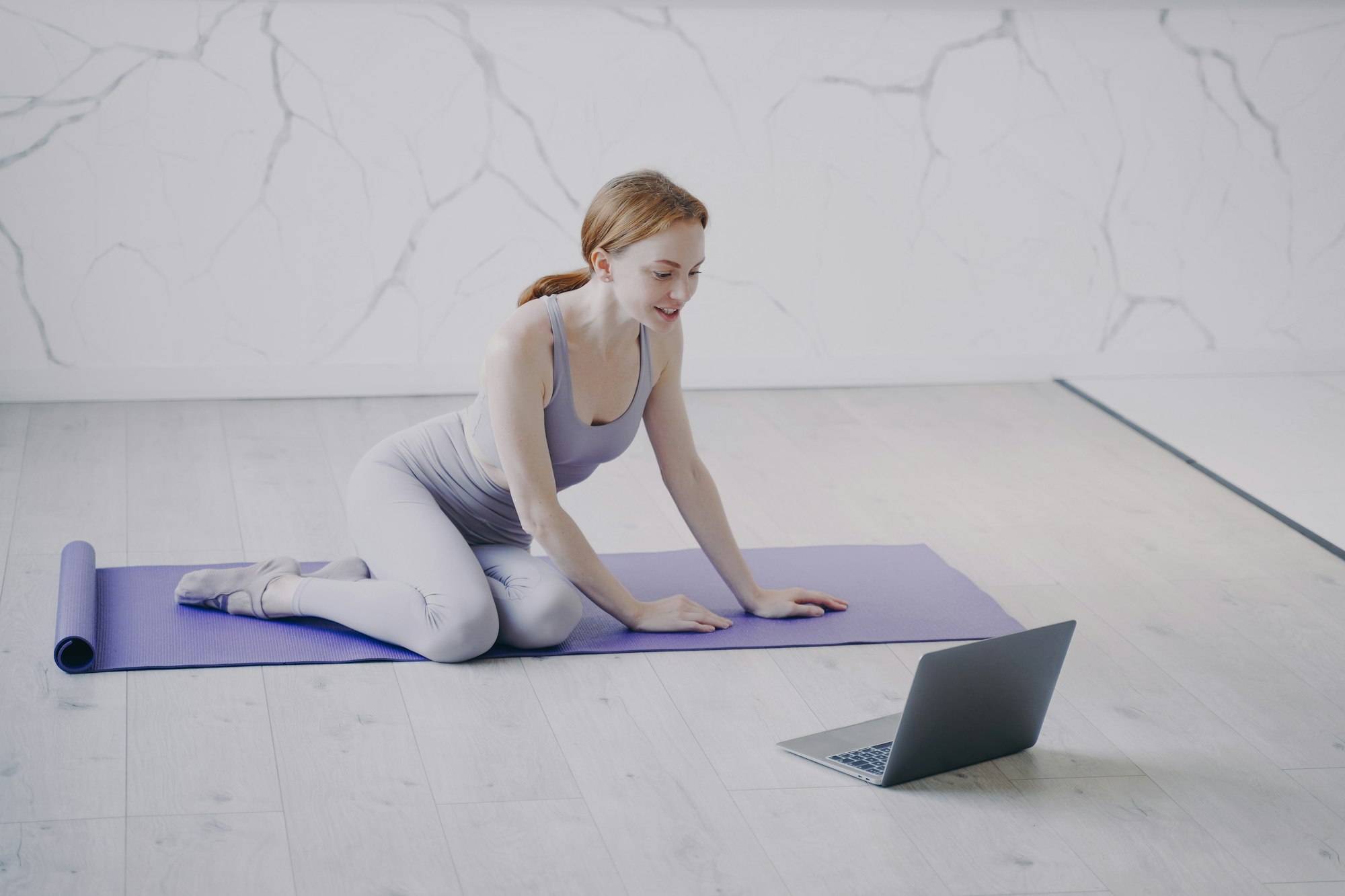 Young woman practicing yoga internet fitness lesson on self isolation. Home online classes.